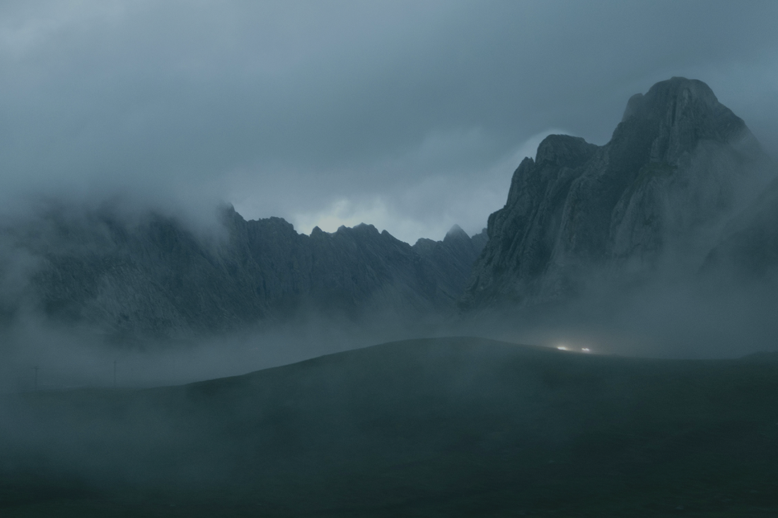 A fog-covered mountain at night with a single pair of headlights visible on the valley floor, surrounded by thick dark cloud — from a BRÍ Wellness blog post on brain fog, cognitive fatigue, and what actually helps when your thinking feels slow and heavy.